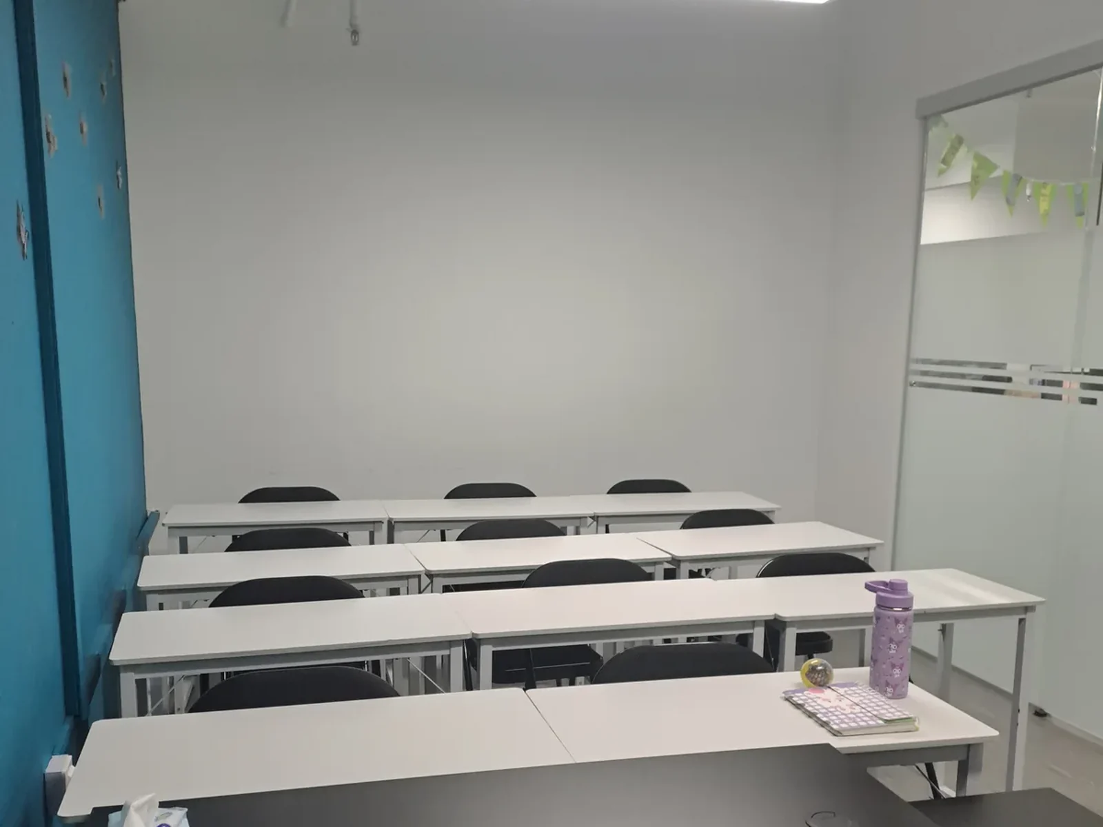 Rows of desks in the blue classroom, ready for the lesson